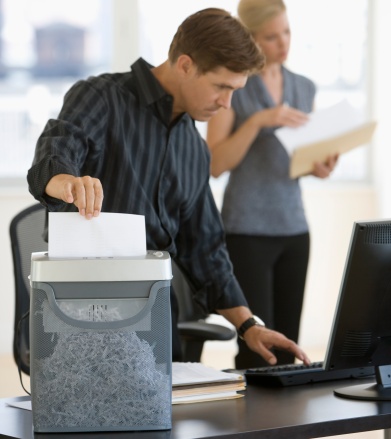 Man shredding documents in an office shredder